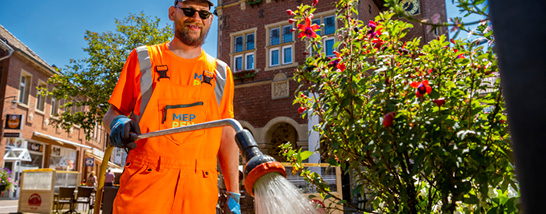 BBH-Mitarbeiter mit Sonnenbrille gießt Blumen in der Fußgängerzone&nbsp;&copy;&nbsp;Schöning Fotodesign