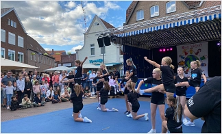 Kindergruppe zeigt akrobatische Übungen auf dem Marktplatz, umringt von vielen Menschen.