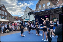 Kindergruppe zeigt akrobatische Übungen auf dem Marktplatz, umringt von vielen Menschen.