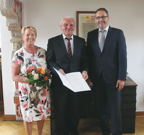 Stadtkämmerer Josef Schnieders (Mitte) wird von Bürgermeister Helmut Knurbein (rechts) in den Ruhestand verabschiedet. Links im Bild seine Ehefrau. © Stadt Meppen